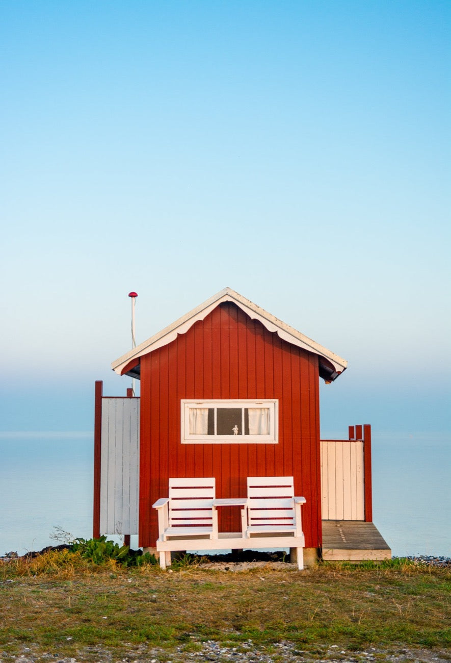 Et rød badehus på Vesterstrand i Ærøskøbing på Ærø med et spejlblankt hav i baggrunden som går i ét med himlen