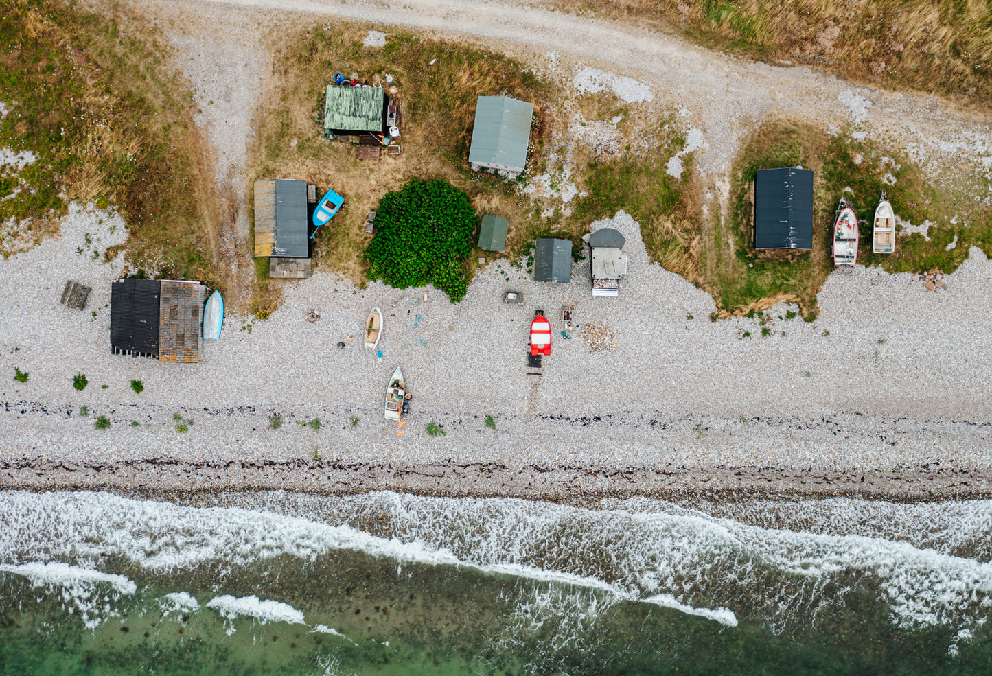 Charmerende rå fiskerhytter ved Vitsøs kystlinje i blæsevejr set fra oven