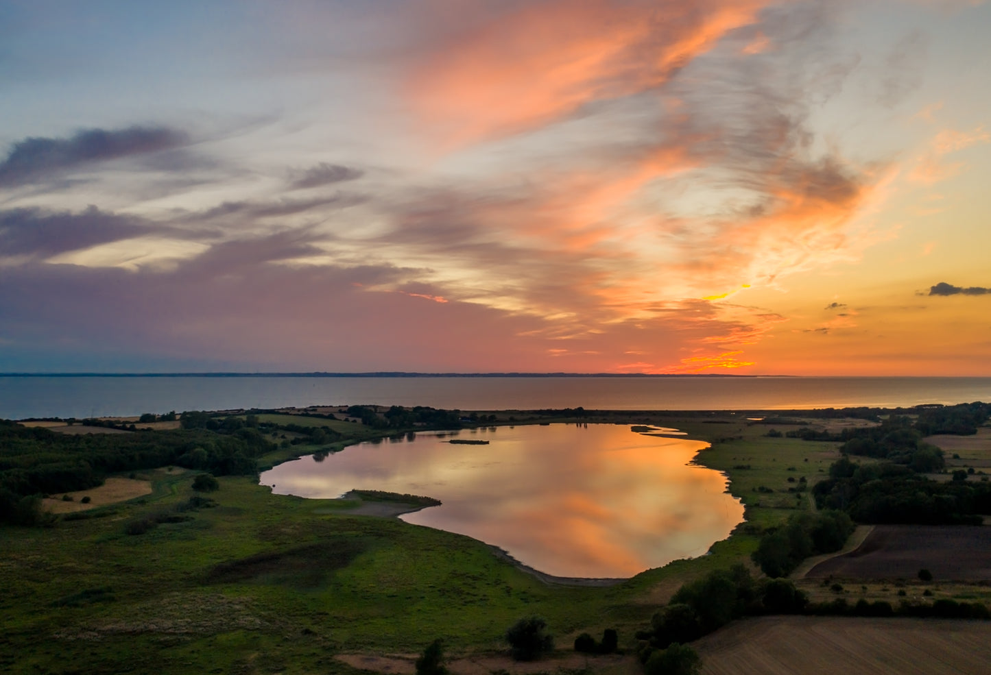 Solnedgangens eksplosion af farver spejler sig i den blanke sø Vitsø på Ærø, så det ser helt eventyrligt ud. Farverne er nærmest akvarel-agtige.