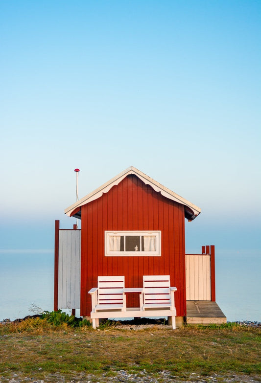 Et rød badehus på Vesterstrand i Ærøskøbing på Ærø med et spejlblankt hav i baggrunden som går i ét med himlen
