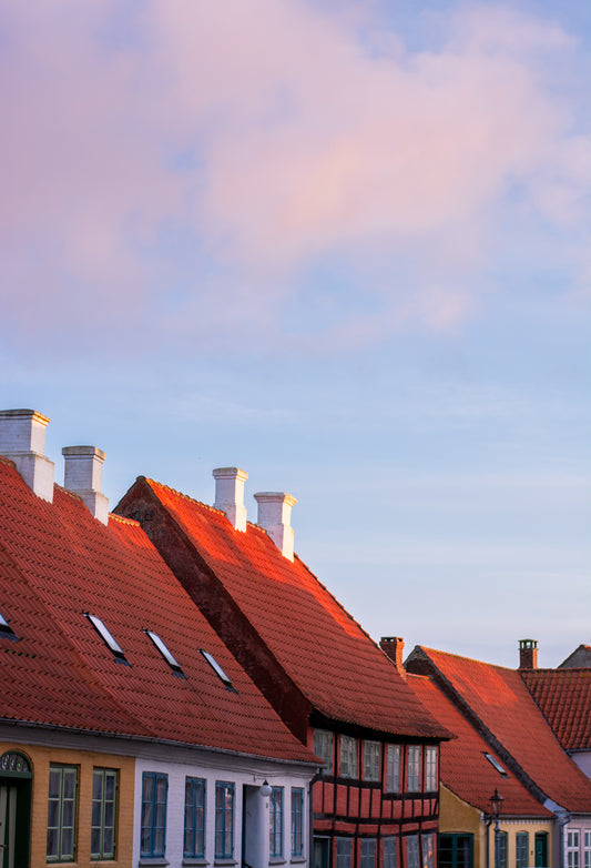 tage og skorstene på 4-5 af Ærøskøbings gamle huse ses her i et rødt skør fra solnedgangen. Blå himmel ovenover