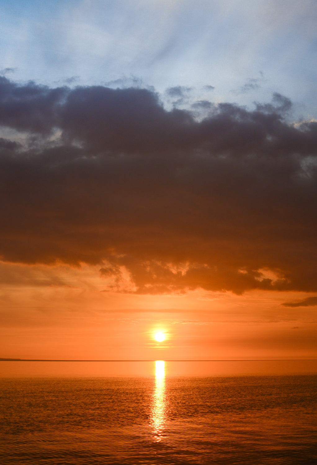 En solnedgang hvor solen hænger lavt og reflekteres i havet